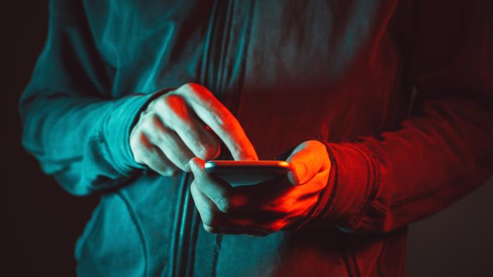 Hände am Smartphone, alles gehüllt in rotes Licht
