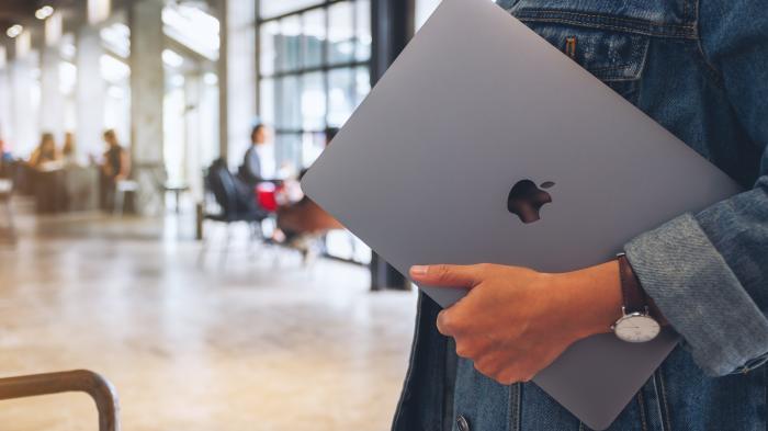 Frau hält MacBook in der Hand